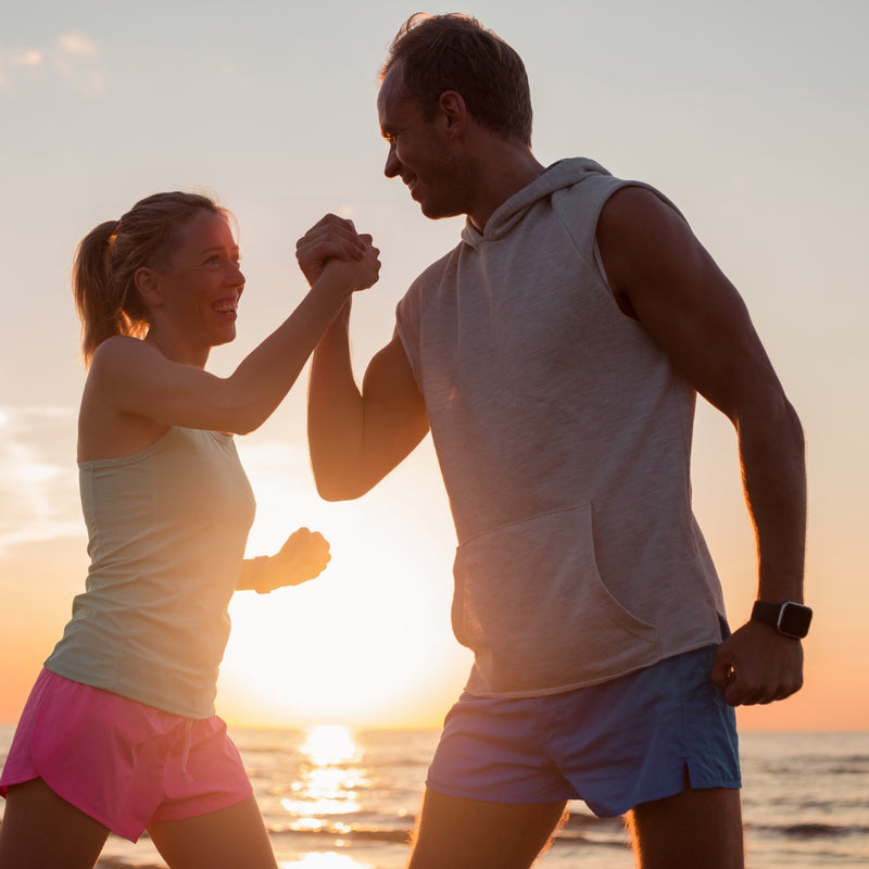 Couple holding hands on a beach at sunset