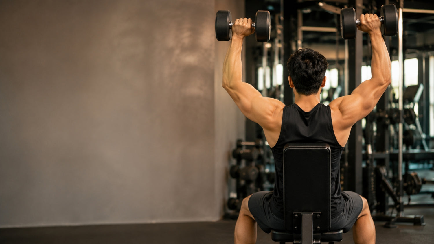 Man exercising with dumbbells in a gym setting